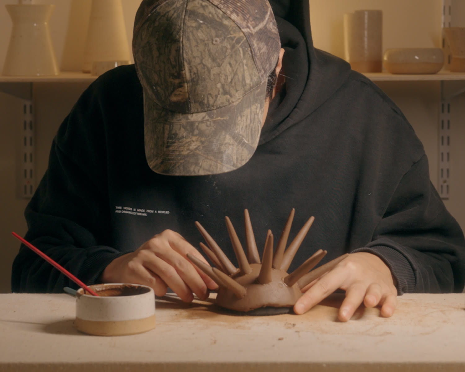 Working at the bench, attaching spikes to a bowl that is most of the way covered